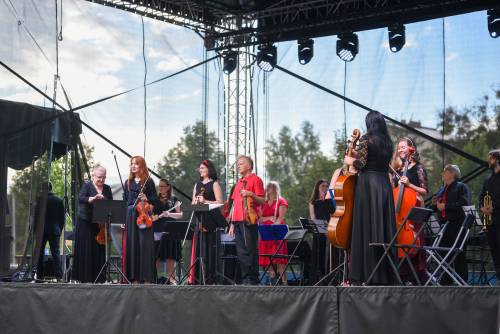 Muzycy podczas koncertu na scenie. Stroje czarno-czerwone.