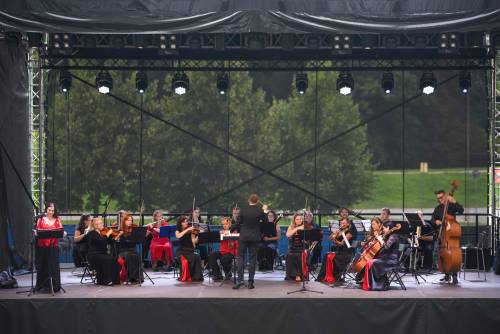 Muzycy podczas koncertu na scenie. Stroje czarno-czerwone. Szeroki kadr.