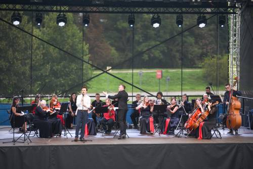 Muzycy podczas koncertu na scenie. Stroje czarno-czerwone. Szeroki kadr.