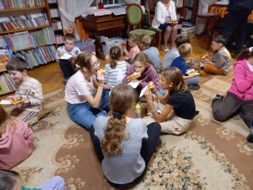 Uczestnicy siedzą na podłodze i jedzą pizzę. Zbliżenie.