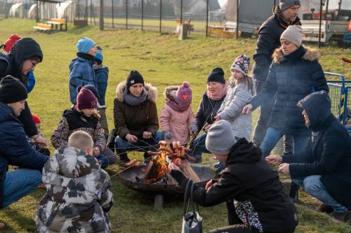 Dzieci przy ognisku smażą kiełbaski.