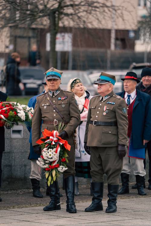 Kombatanci stojący przed tłumem z kwiatami.