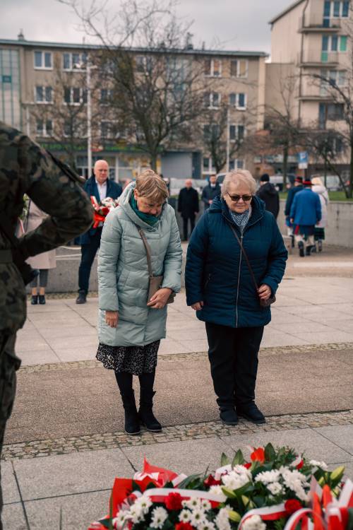 Mieszkańcy składają kwiaty pod pomnikiem Nike.