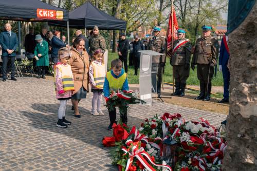 Przedszkolaki składają kwiaty podczas obchodów upamiętniających zbrodnię katyńską w obstawie żołnierzy.