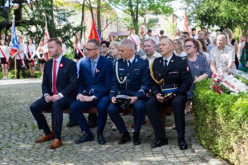 Goście podczas obchodów rocznicy uchwalenia konstytucji 3 maja. 4 mężczyźni siedzą na ławce.