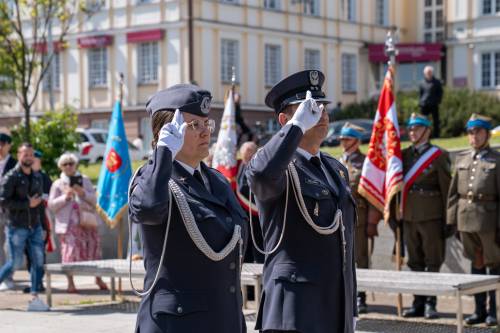 Policjanci salutują przed pomnikiem Nike na placu Jana Pawła II. W tle budynek Starostwa Powiatowego.