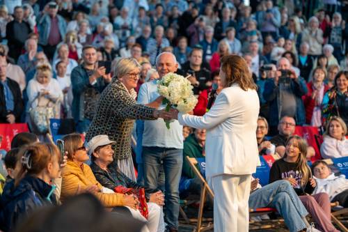 Widownia podczas koncertu. Artystka wśród publiczności otrzymuje kwiaty.