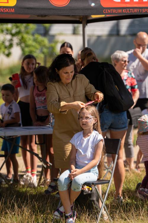 Animatorka zawiązuje dziewczynce warkoczyk.