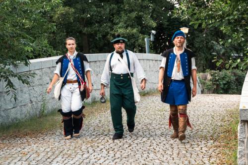 Zdjęcie przedstawia aktywności podczas Drop Zone w Faktorii Handlowej. Trzech rekonstruktorów idzie przez kamienny mostek.