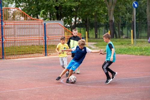 Dzieci grają w piłkę podczas festynu Wakacje w mieście na boisku przy ulicy Tysiąclecia.