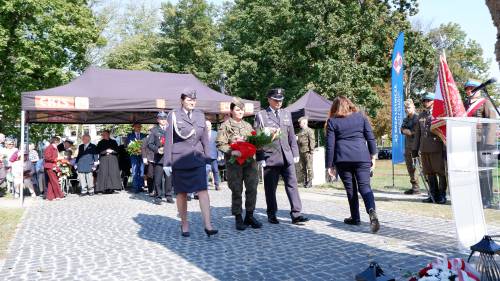 Składanie kwiatów pod pomnikiem przez gości.