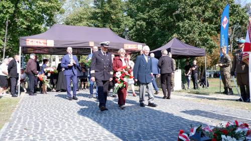 Składanie kwiatów pod pomnikiem przez gości.