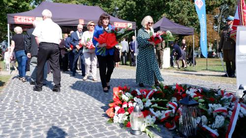 Składanie kwiatów pod pomnikiem przez gości.