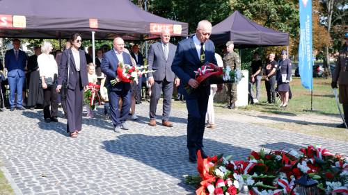 Składanie kwiatów pod pomnikiem przez gości.