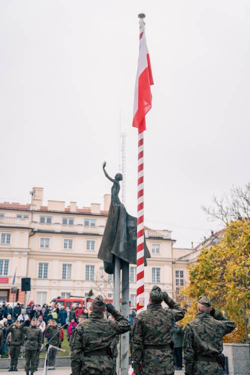 Flaga na maszcie, w tle pomnik Nike.