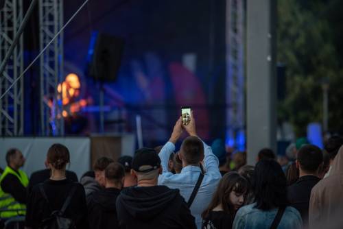 Punliczność oglądająca koncert, jeden z widzów wykonuje zdjęcie telefonem