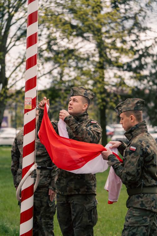 Zakładanie flagi na maszt z flagą Rzeczypospolitej Przemówienie podczas obchodów upamiętniających zbrodnię katyńską w obstawie żołnierzy.