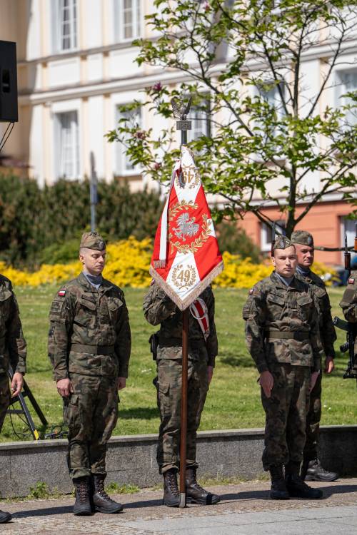 Żołnierze z pocztem sztandarowym na placu Jana Pawła II. W tle budynek Starostwa Powiatowego.