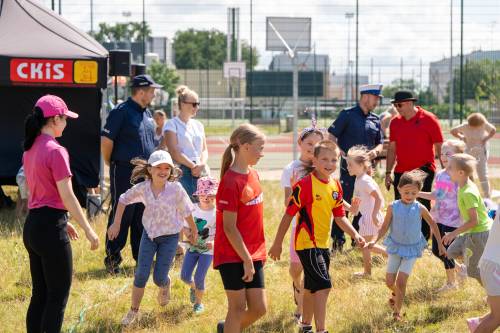 Dzieci podczas zabawy. Policjanci w tle.