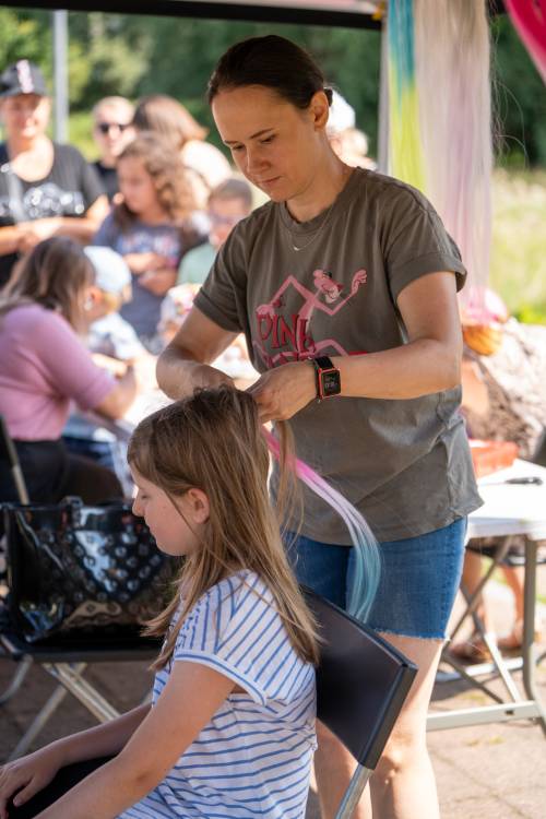 Zaplatanie warkoczyków. Dziewczynka siedzi, kobieta stoi.