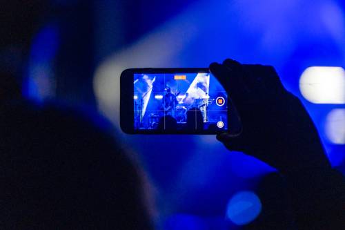 Zdjęcie przedstawia telefon, na którym widać artystów na scenie podczas koncertu Spiętego w Pruszczu Gdańskim.