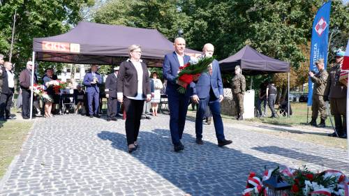 Składanie kwiatów pod pomnikiem przez gości.