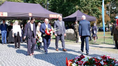 Składanie kwiatów pod pomnikiem przez gości.