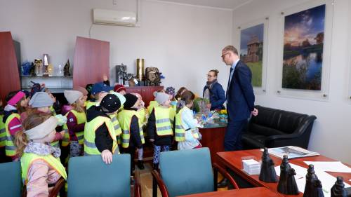 Dzieci odwiedzają Burmistrza Pruszcza Gdańskiego Janusza Wróbla w jego gabinecie. Po lewej stronie stoją dzieci w odblaskowych, żółtych kamizelkach (bokiem-tyłem).