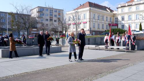 Goście składają kwiaty pod pomnikiem Nike. Z kwiatami senator i posłanka.