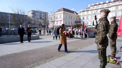 Goście składają kwiaty pod pomnikiem Nike. Z kwiatami posłanka.