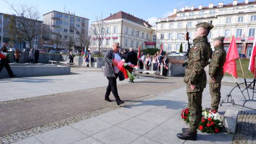 Goście składają kwiaty pod pomnikiem Nike. Z kwiatami przedstawicielka Rady Miasta.