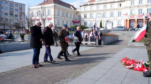 Goście składają kwiaty pod pomnikiem Nike. Z kwiatami przedstawiciele organizacji kombatanckich.