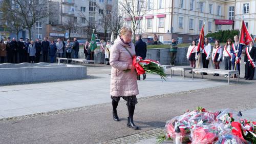 Goście składają kwiaty pod pomnikiem Nike. Z kwiatami przedstawicielka mieszkańców.
