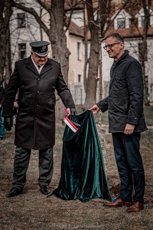 Dwóch mężczyzn odsłania tablicę pamiątkową.