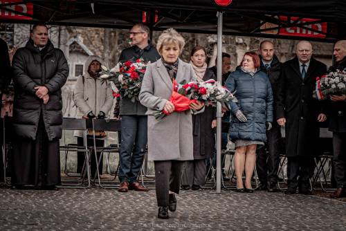 Goście składają kwiaty podczas uroczystości.