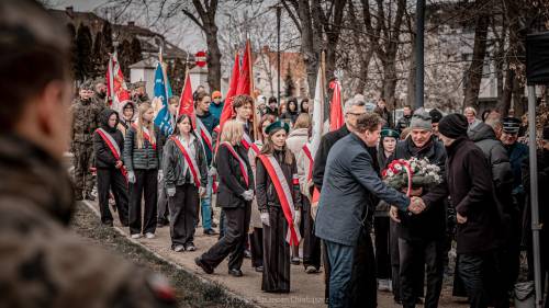 Goście składają kwiaty podczas uroczystości.