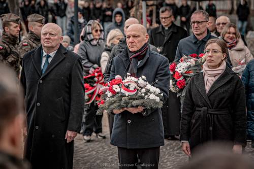 Goście składają kwiaty podczas uroczystości.