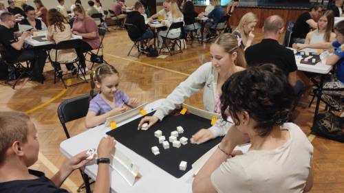 Rozgrywki Rummikub, zawodnicy siedzą przy stolikach