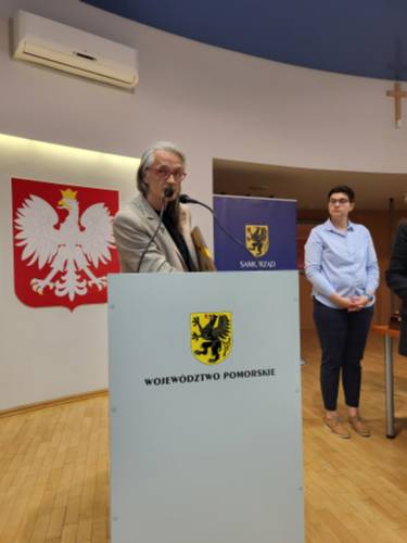 Andrzej Ślusarczyk przemawia. W tle kobieta.