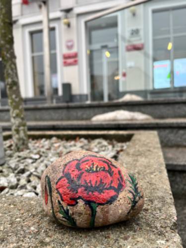 Kamień z namalowanym makiem leży na murku przed urzędem miasta.