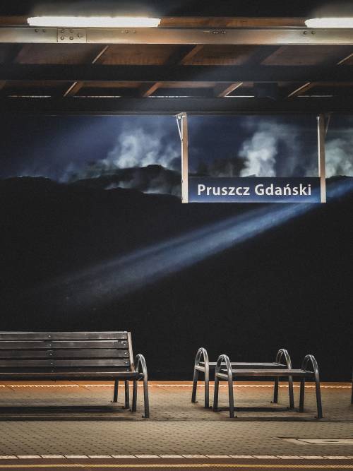 Smuga światła na peronie. Napis Pruszcz Gdański i ławeczki.