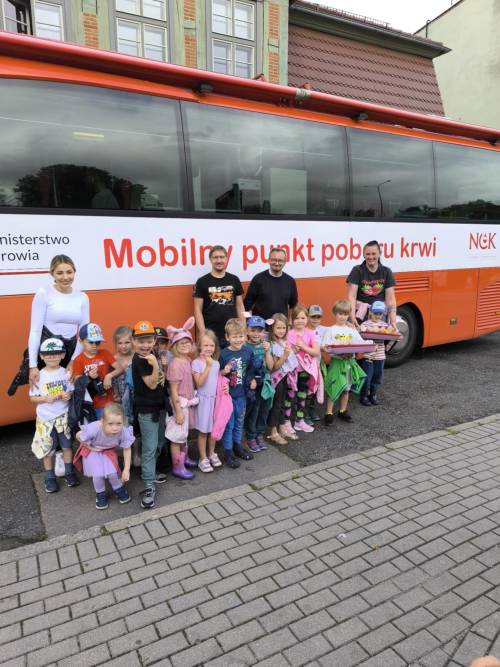 Organizatorzy, przedszkolaki i nauczycielki przed busem.