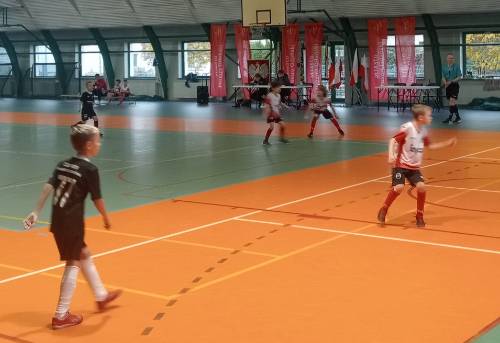 Zdjęcie przedstawia dynamiczną scenę meczu piłki nożnej halowej