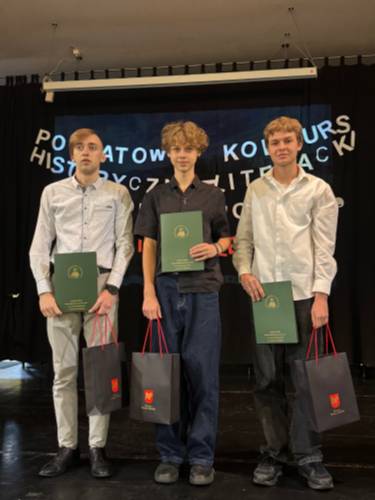 Trzej laureaci konkursu, trzymający dyplomy oraz nagrody rzeczowe