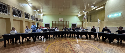 Grupa nastoletnich uczniów siedzących przy stołach