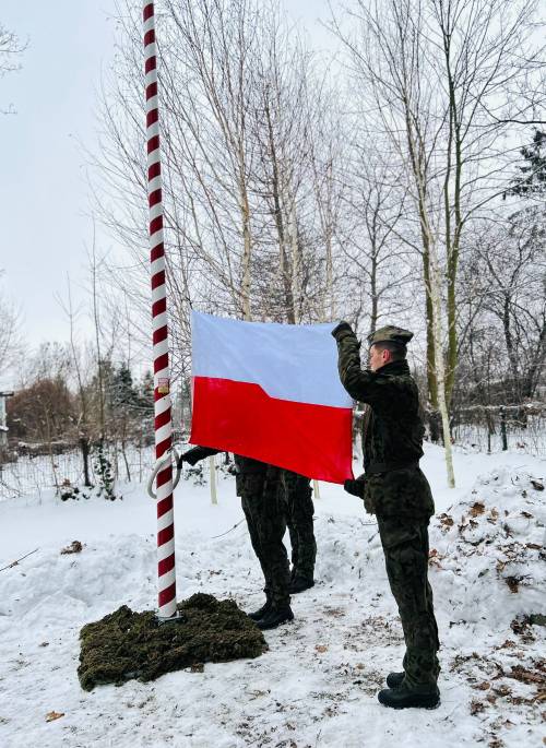Żołnierz trzyma biało - czerwoną Flagę Polski