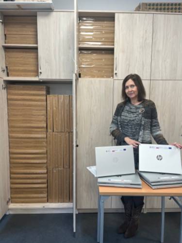 Kobieta trzyma nowy laptop marki HP, stojący na biurku.