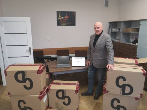 Mężczyzna stoi przy kartonach ze sprzętem elektronicznym.