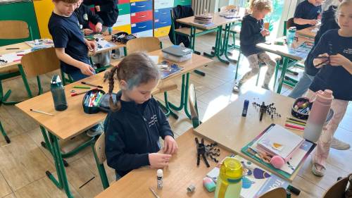 Dzieci wykonują pająki z papieru i włóczki