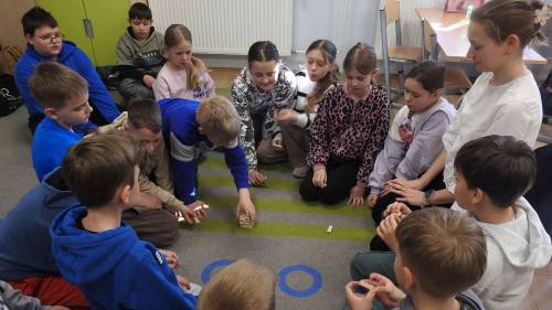 Dzieci siedzą na podłodze i wykonują zadania